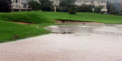 A flooded golf course with buildings in the background.
