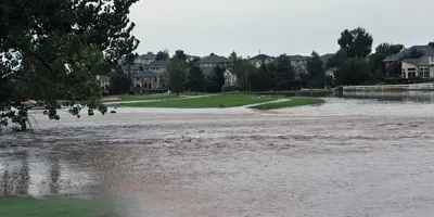 A flooded golf course with buildings in the background.