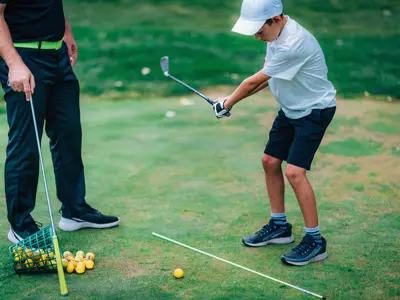 An adult helps a child practice swinging a golf club.