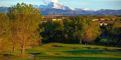 A golf course with trees and mountains in the background.