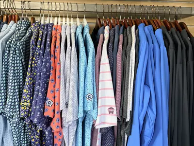 A rack of shirts and hats at a shop.