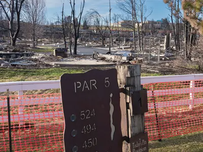 A flooded golf course with a sign reading "Par 5," and fencing in the foreground.